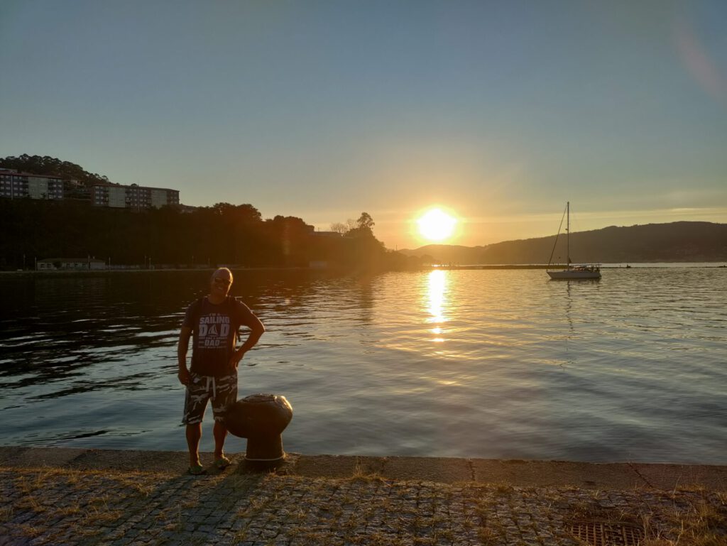 Frank steht am Ufer. Im Hintergrund geht die Sonne unter.